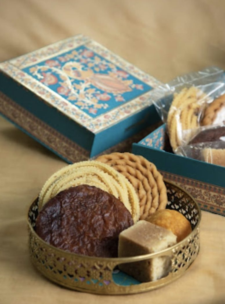 Adhirasam, murukku, mysore pak, and laddu set in a brass tray beside the Pattappas box.